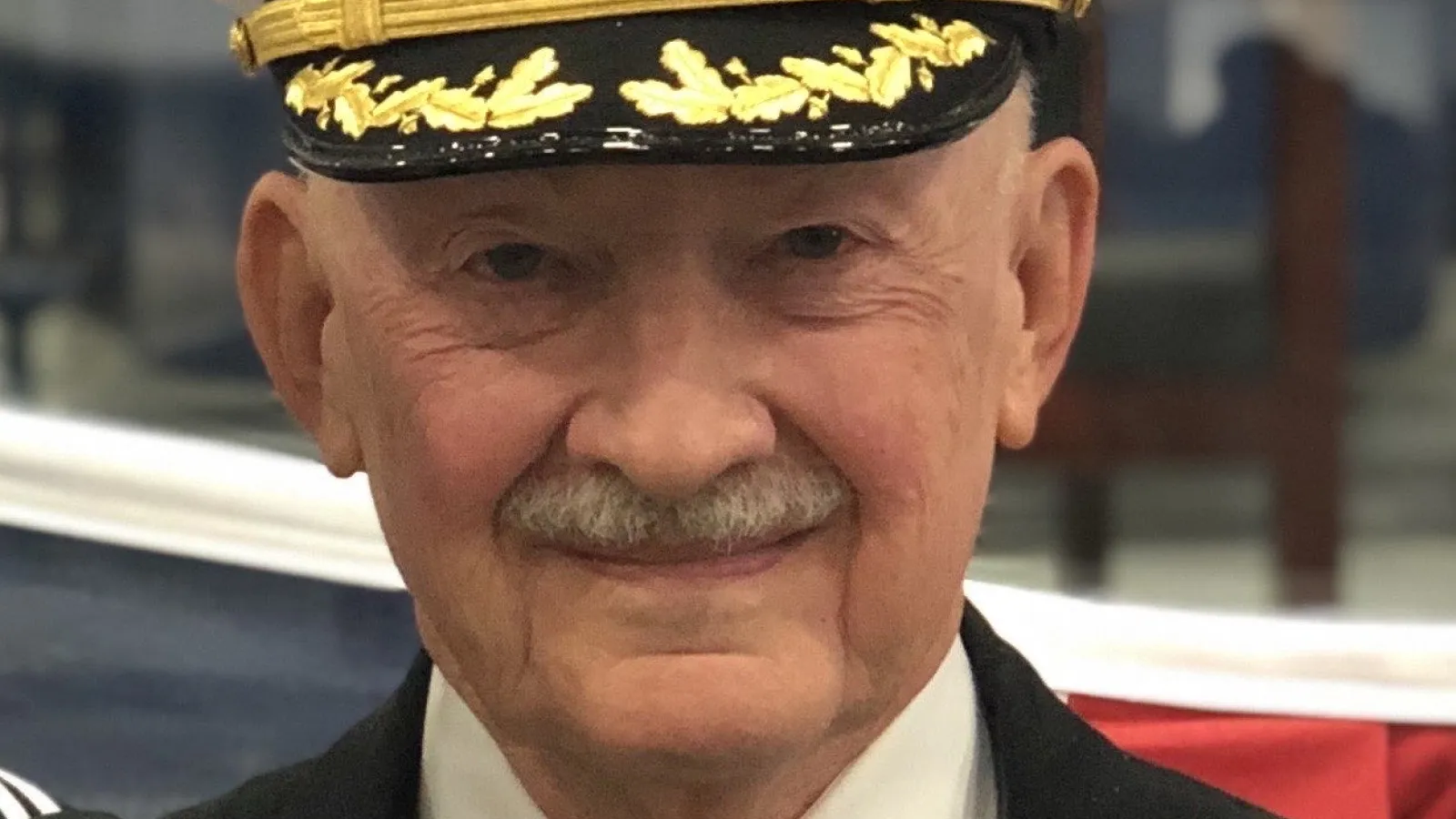 Captain James G Connell Junior in a Navy captain's cap and suit, smiling.